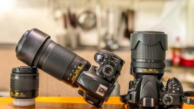 Close-up of DSLR cameras and lenses on a wooden table indoors, ideal for photography enthusiasts.