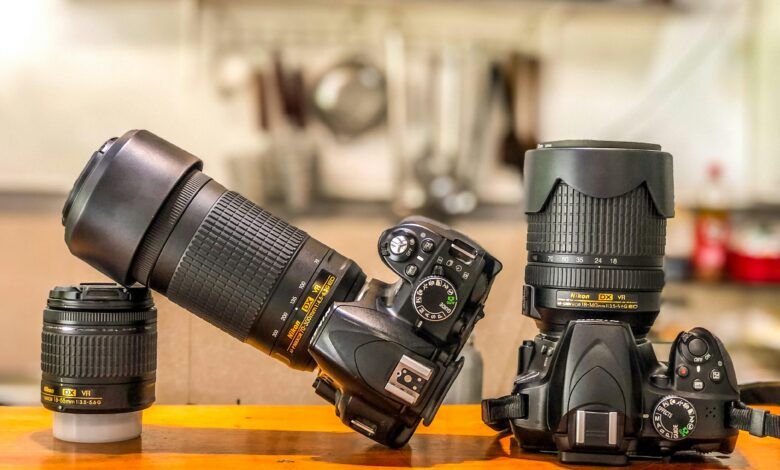 Close-up of DSLR cameras and lenses on a wooden table indoors, ideal for photography enthusiasts.