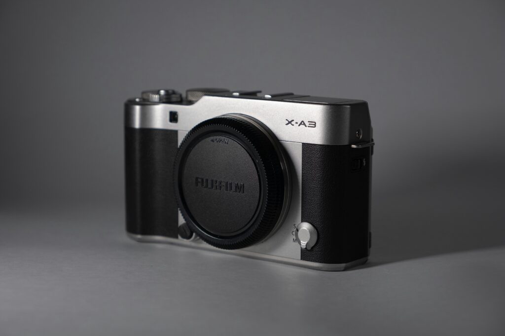 Close-up of a vintage-style mirrorless camera on a gray background, showcasing its design.