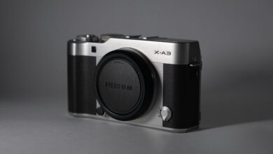 Close-up of a vintage-style mirrorless camera on a gray background, showcasing its design.