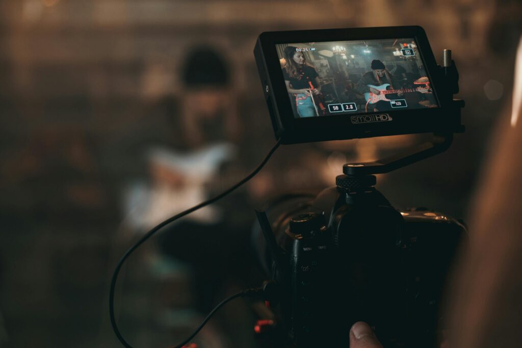 A cinematic close-up of filming a rock band performance with focus on camera screen. Just before video editing.