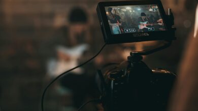 A cinematic close-up of filming a rock band performance with focus on camera screen.
