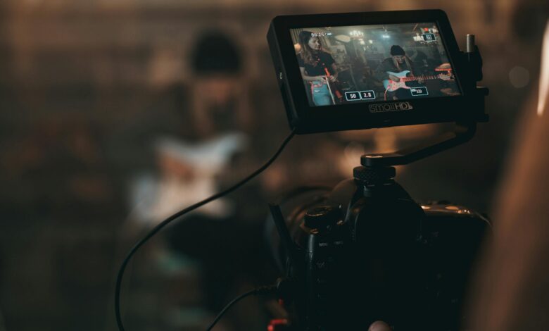 A cinematic close-up of filming a rock band performance with focus on camera screen.