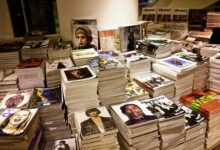Huge stacks of diverse fashion and lifestyle magazines piled high in an indoor store setting.